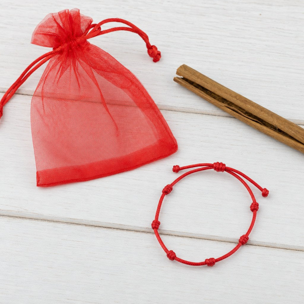 Pulsera de los 7 Nudos con su bolsa de organza roja y rama de canela